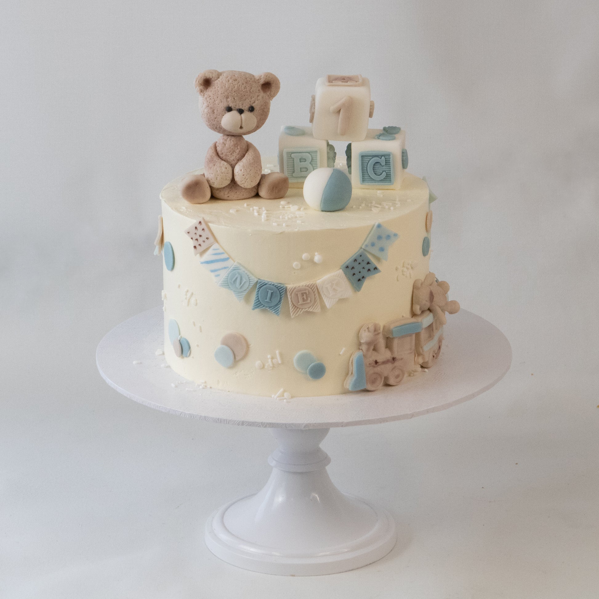 Babydier kindertaart met teddy beer en speelgoeddecoraties
