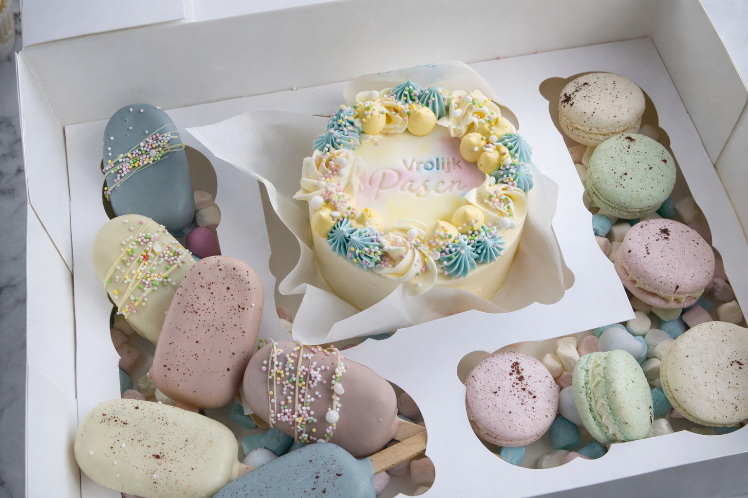Luxe paas dessert box met Vrolijk Pasen taart, macarons en cakesicles – paas lekkernijen met lokale bezorging in Zeist en regio Utrecht.